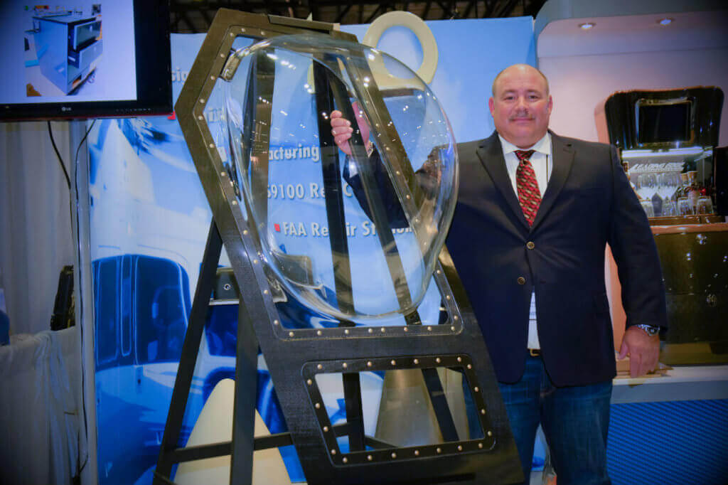Brian Arni, president and chief operating officer of Leading Edge Composites, stands with a bubble door his company developed with Columbia Helicopters for Model 234 and Model CH-47D Chinooks. Ben Forrest Photo