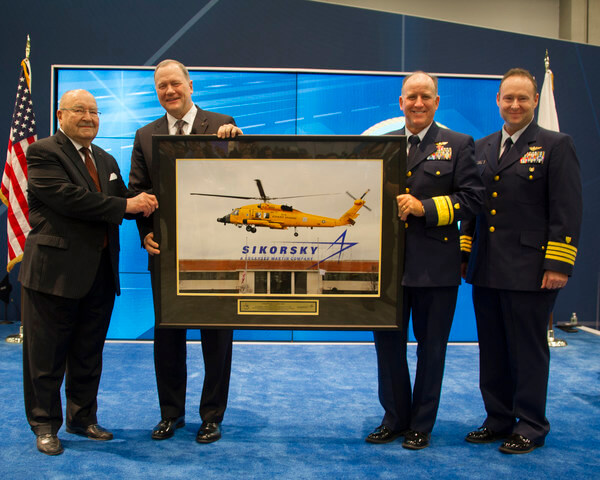Sergei Sikorsky, left, and Sikorsky president Dan Schultz present U.S. Coast Guard aviators Rear Adm David Callahan and Capt Joe Kimball with a framed photo of an MH-60T Jayhawk helicopter taking off from Sikorsky's Stratford, Connecticut, headquarters on Dec. 7, 2016. The aircraft is painted chrome yellow to commemorate the U.S. Coast Guard's aviation centennial 