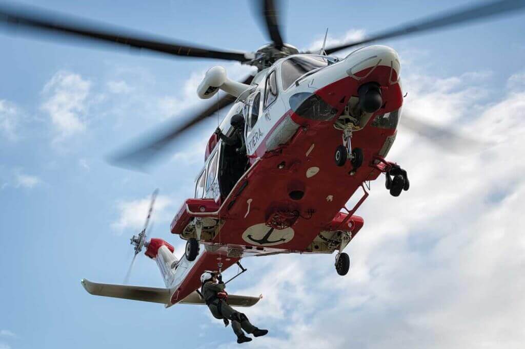 A rescue swimmer is lowered from the AW139 during a training exercise at a small airfield.
