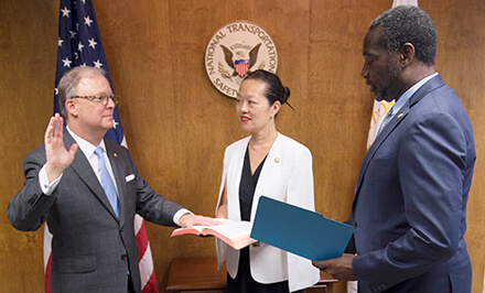 Man is sworn in with woman and other man looking on.