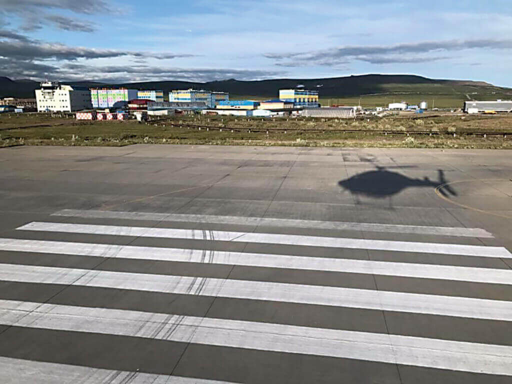Helicopter casts a shadow on the tarmac.