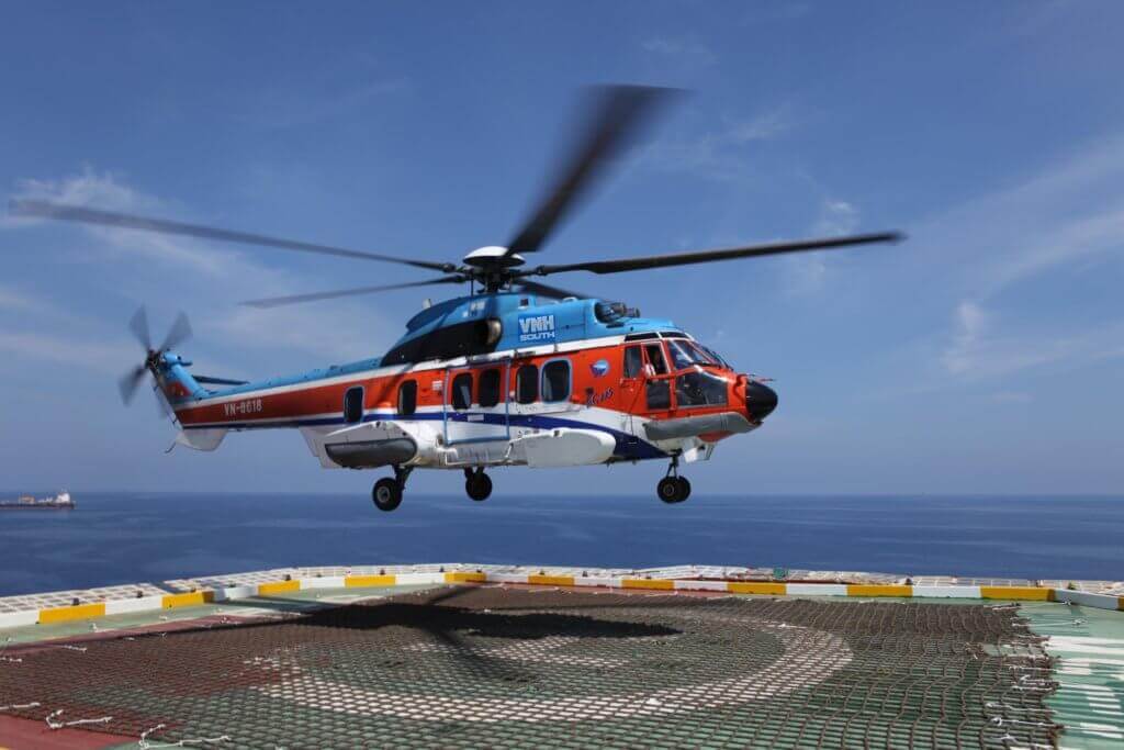 A VNH South Airbus H225 helicopter hovers over a helipad.