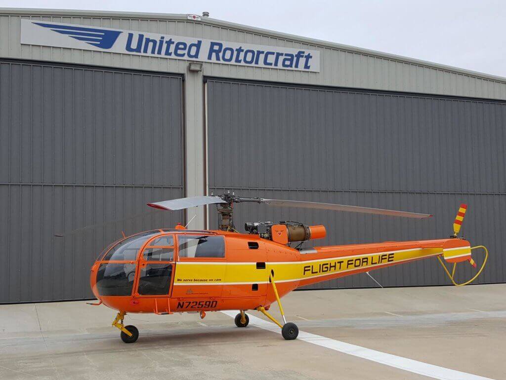 Orange-and-yellow Alouette III in front of United Rotorcraft hangar