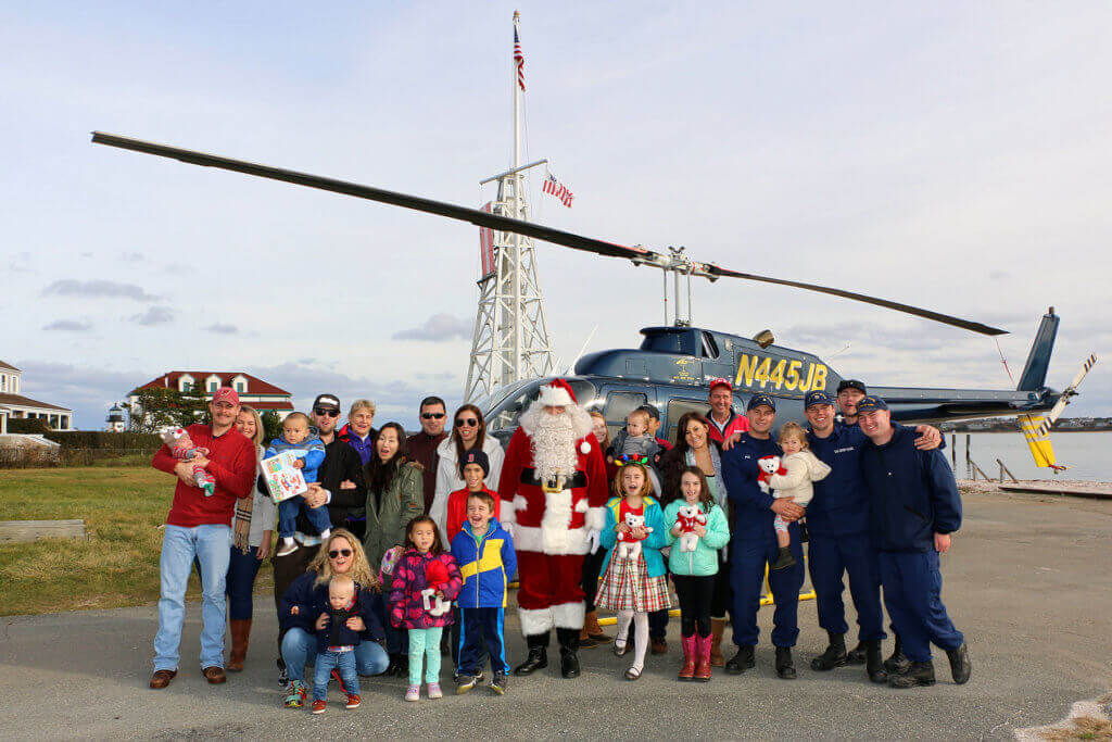 USCG families are gathered at Coast Guard Station Brant Point with Santa Claus, in front of a Bell 206B JetRanger III donated by JBI Helicopters. Friends of Flying Santa Photo