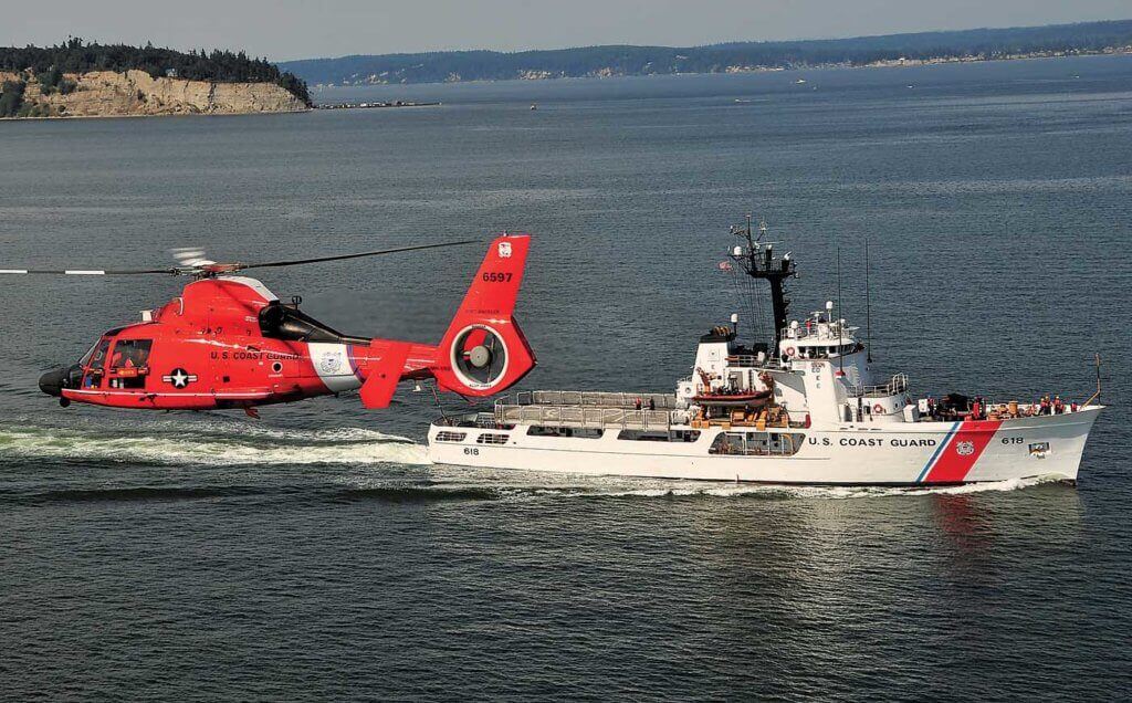 A MH-65D works around a USCG 210-foot cutter. The ships, boats, and aircraft of the USCG work together to keep the U.S. safe. Skip Robinson Photo