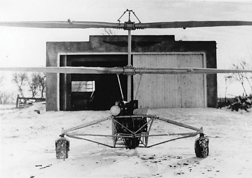 A front view of the Froebe helicopter in front of a farm building. Note the small fuel tank on the side of the engine. Royal Aviation Museum of Western Canada Photo
