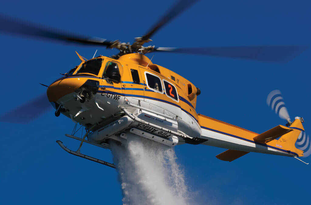A Bell 412 operated by Wisk Air Helicopters demonstrates a water drop with its 375-gallon (1,420-liter) Simplex Belly Tank. The aircraft is one of three 412s in the operator's fleet, and is working on a major firefighting contract this summer. Mike Reyno Photo