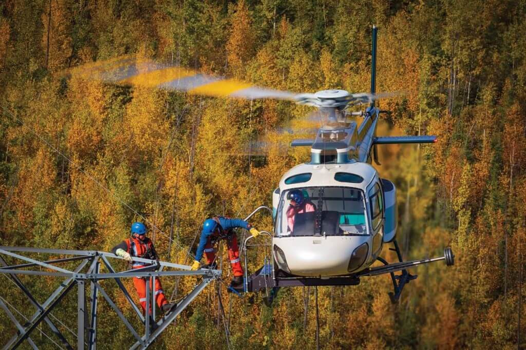A lineman completes a transfer onto a tower from Slave Lake Helicopters Airbus H125. The company uses its custom-designed AStep to perform these operations. Heath Moffatt Photo