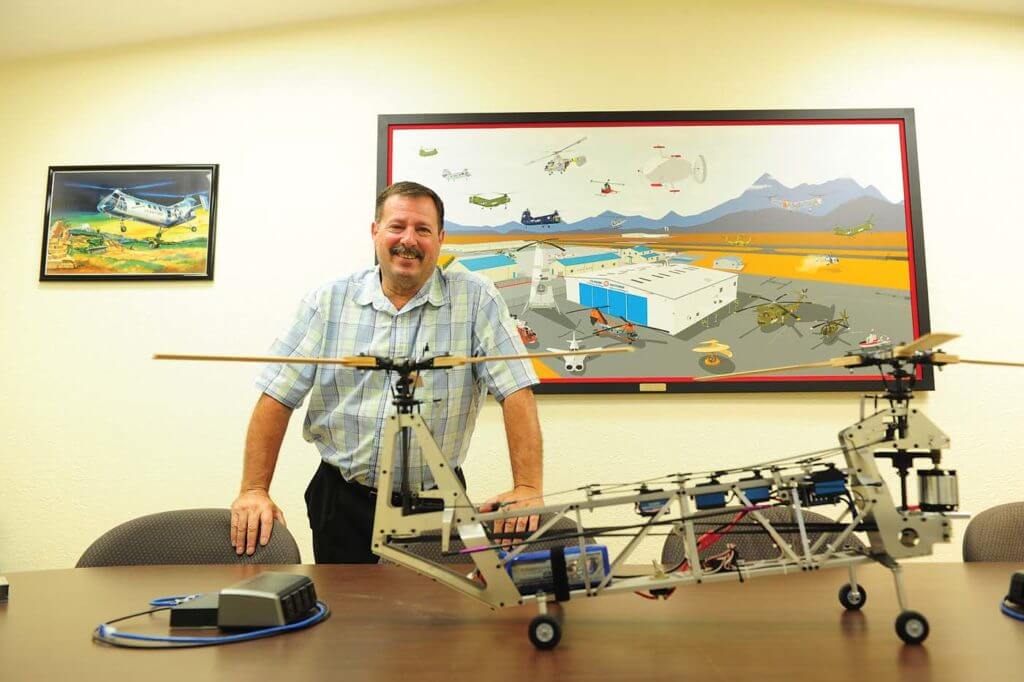 Mark DiCiero stands by a tandem rotor remote-controlled helicopter in front of a painting of the museum. His passion for helicopters, matched that of the museum's volunteers, has brought Classic Rotors to where it is today. Skip Robinson Photo