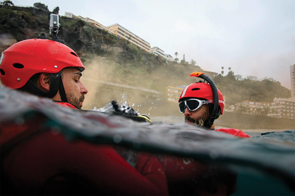 Rescue swimmer Juan (left) checks that Michael's harness is securely connected to the cable before signaling to the winch operator that he is clear to winch. Lloyd Horgan Photo