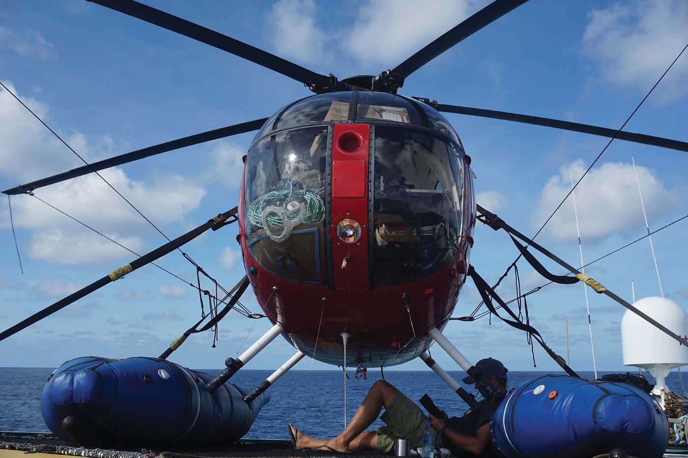 As a tuna boat helicopter pilot, there is plenty of time to sit back and relax. Here, the author rests under his MD 500 while reading a book. Matthew Hayes Photo
