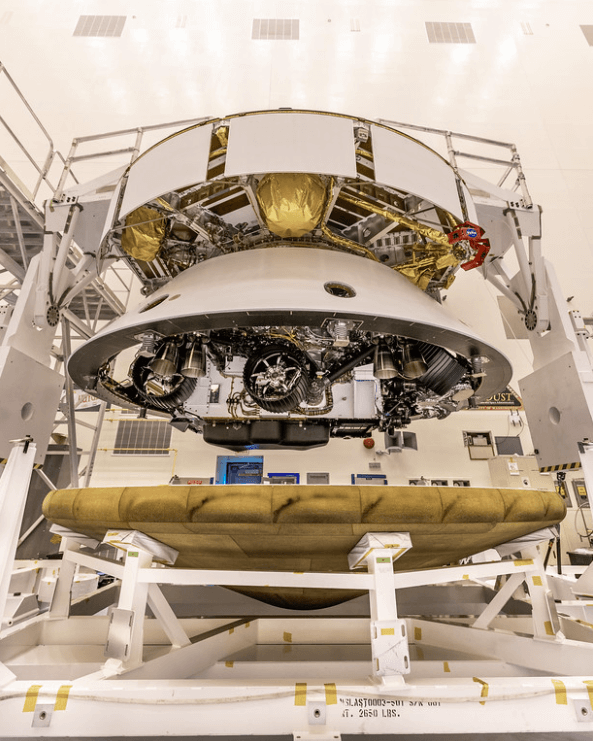 The Mars 2020 Perseverance rover mission's disk-shaped cruise stage sits atop the bell-shaped back shell, which contains the powered descent stage and Perseverance rover. Below is the brass-colored heat shield that is about to be attached to the back shell. NASA/JPL-Caltech/KSC Photo